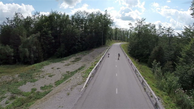 Two skaters fast riding from under camera on straight road