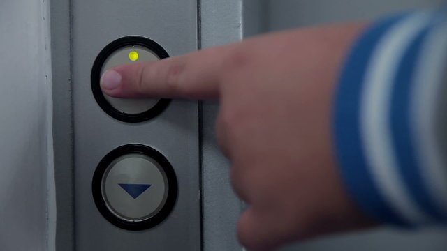 Youngster palm presses the button on a elevator control