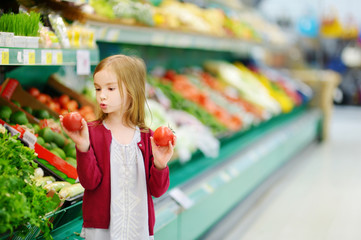 Little girl choosing tomatoes in a store