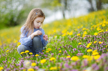Fototapeta premium Adorable girl in blooming dandelion flowers