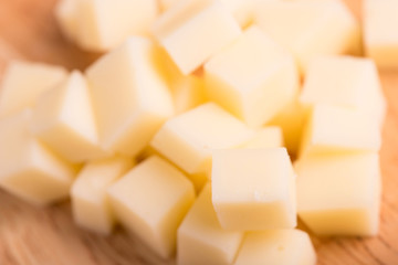 cheese cubes close up on wooden background - selective focus