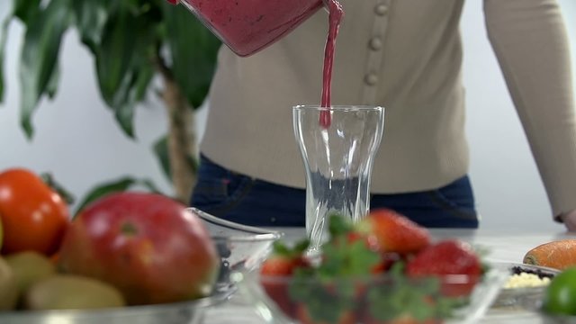 Pouring berry smoothie into the glass