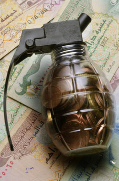 Close up of Transparent grenade filled with coins on emirati dirham notes
