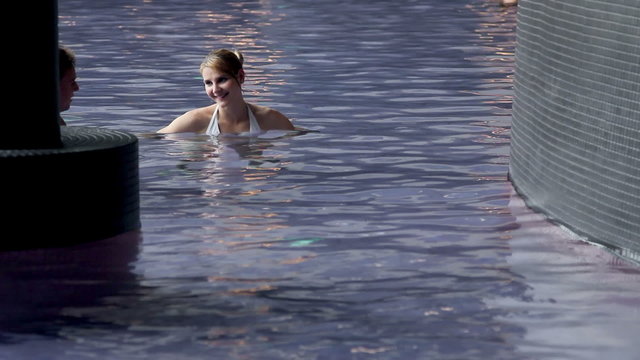 young couple in pool chit chatting