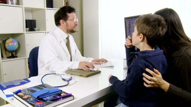 Doctor talking to child and mother in office