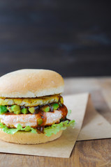 Homemade fish burger with salmon, avocado and pineapple.Close up