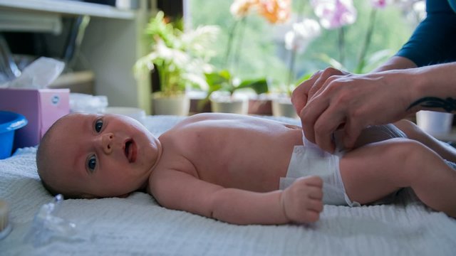 Hands changing baby's diaper