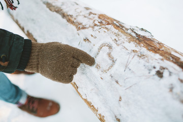 Man draw heart symbol on snow in forest
