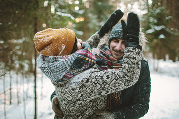 Young hipster couple having fun in winter forest