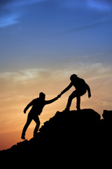 Silhouette of helping hand between two climber