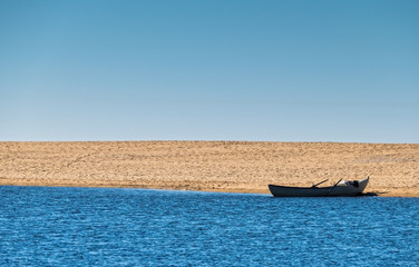 Obraz premium Solo Rowboat Moored on Sandy Beach