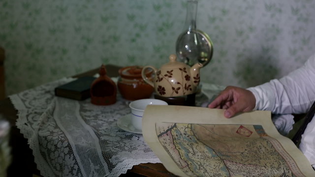 Man getting his cup of tea and looking at an old map