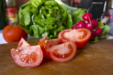 Tomatoes, salad and radishes on the cutting board