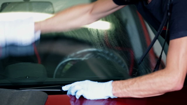 Male cleans the windscreen with a bright cloth