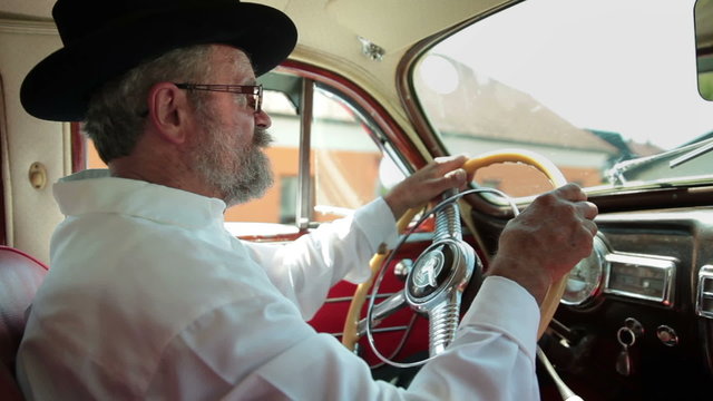 Old farmer is driving a vintage car 