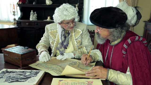 Close shot of two medieval men talking about old map