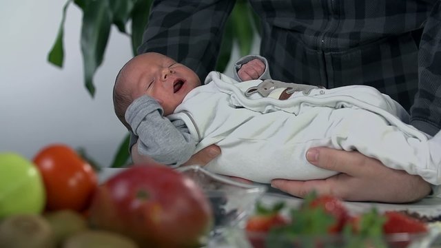 Holding the baby in front of all the sweet things on the table