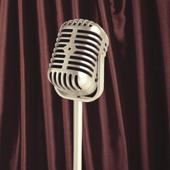 Silver retro microphone on brown curtain background