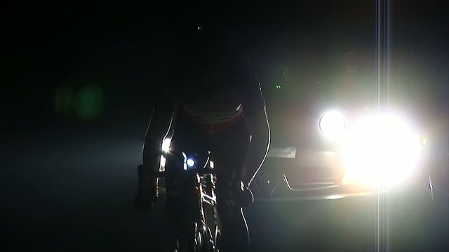 Cyclist contestand driving in pitch dark in front of his team truck. Cyclists race across a small Eastern European country called Slovenia.