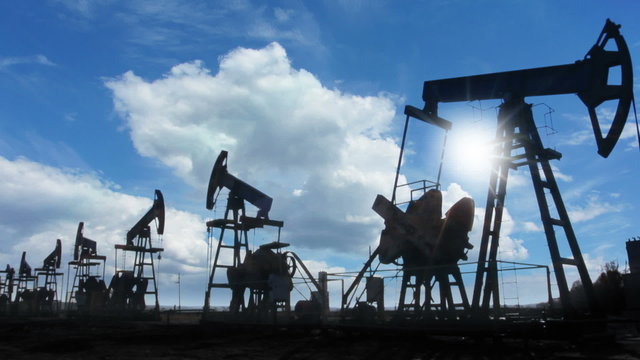 working oil pumps silhouette against timelapse clouds