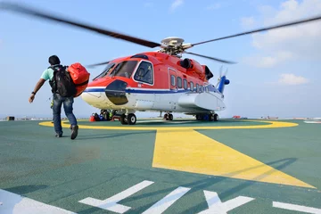 Zelfklevend Fotobehang passagier draagt zijn bagage om aan boord te gaan van een helikopter op booreiland plat © num_skyman