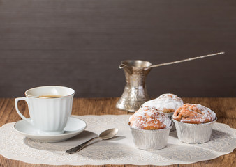 Cup of coffee with tasty muffins and turk for coffee