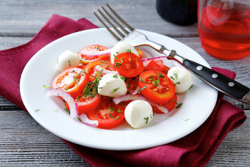 Tomato onion and mozzarella cheese on a white plate