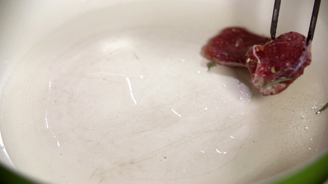Putting a piece of meat into oily pan