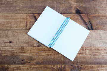 Open notepad with empty pages laying on a wooden table