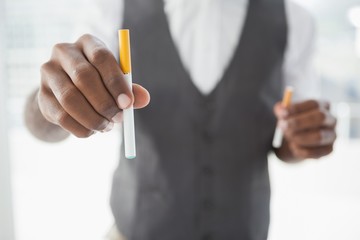 Businessman holding electronic cigarette and cigarette