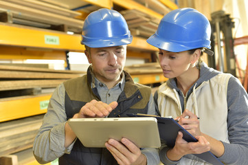 Worker with overseer controling stock in warehouse