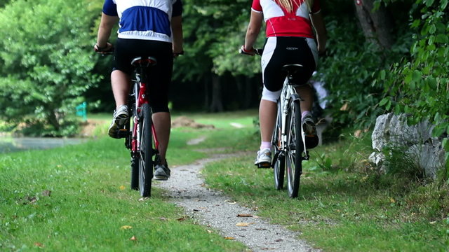 HD1080p: Young couple cycling in nature and passing family that sits on the bench