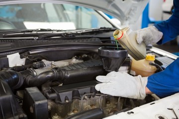 Mechanic pouring oil into car