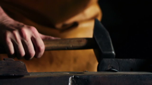 Close up slide shot of blacksmith who shapes metal into final shape