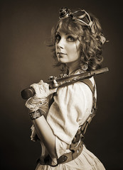 Beautiful redhair steampunk girl with gun looking at camera. Old