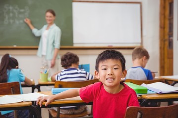 Fototapeta na wymiar Cute pupil smiling at camera in classroom