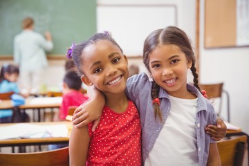 Cute pupils smiling at camera in classroom