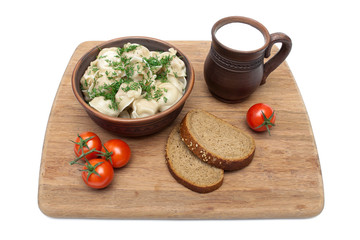 Russian dumplings in a clay bowl on a cutting board. white backg