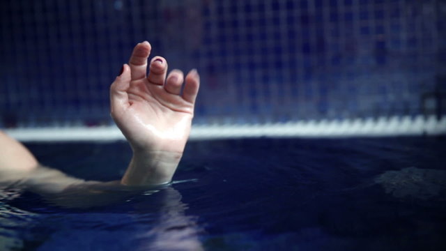 Close up shot of a waving woman hand in the pool  