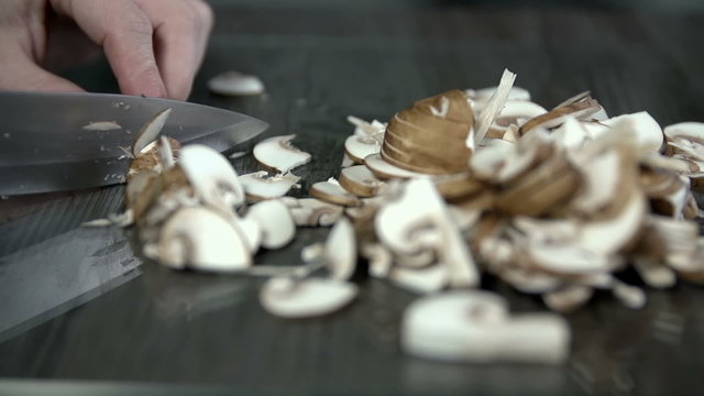 Slicing a bunch of mushrooms into thiny pieces in slow motion