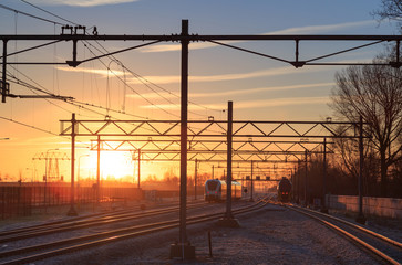 Railroad tracks at a station at a winter sunrise.