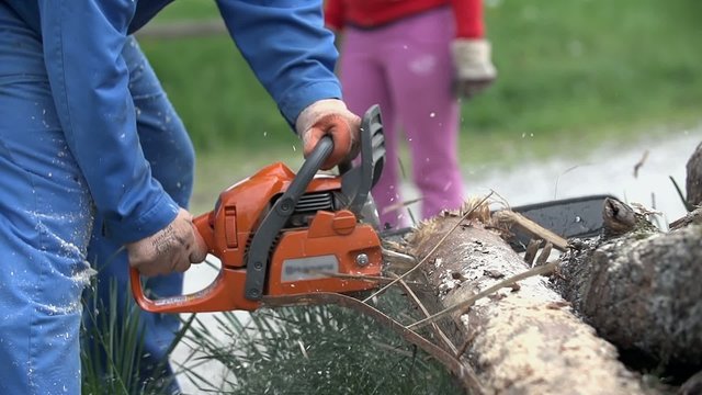 Chainsawing log with sawdust flying around in slow motion
