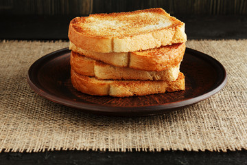 Toast in a clay plate on a wooden table with burlap