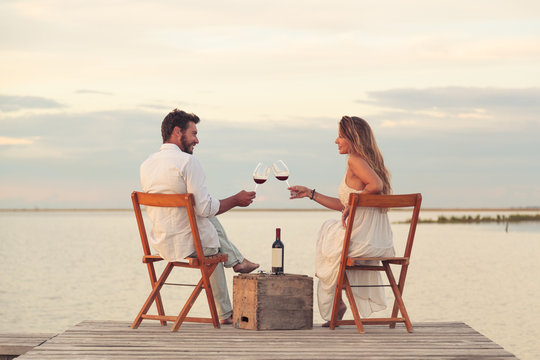 couple drinking red wine at the seaside on a jetty