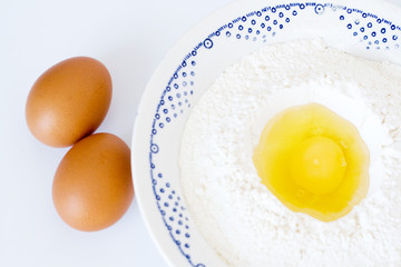 Plate with flour, eggs lying on a white background