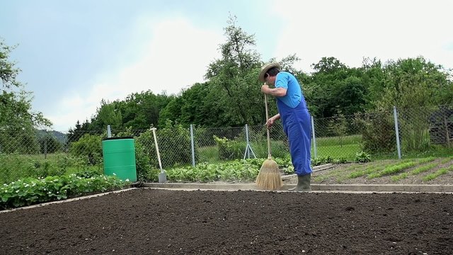 Gardener sweeps the floor in his garden