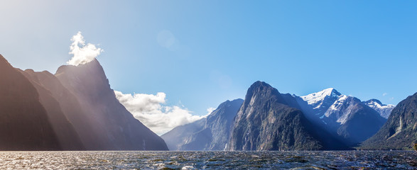 Majestic snow capped peaks of Milford Sound with sun rays. Fiord