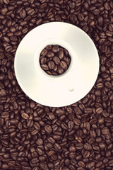Cup of coffee over fresh roasted beans background