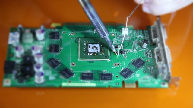 Shot of a man solder a  chip on a graphics card
