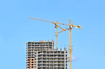 Crane and building construction site against blue sky